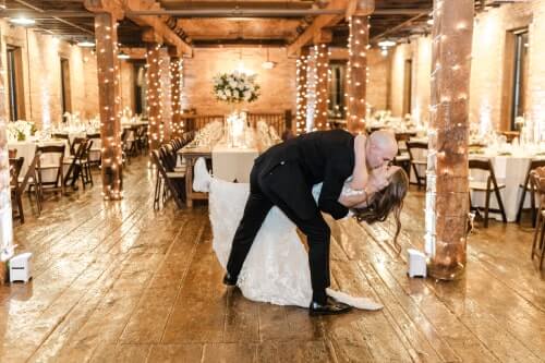 Harrisburg-PA-Wedding-String-Lighting Groom dipping his bride in Harrisburg rustic barn venue with lighting in background