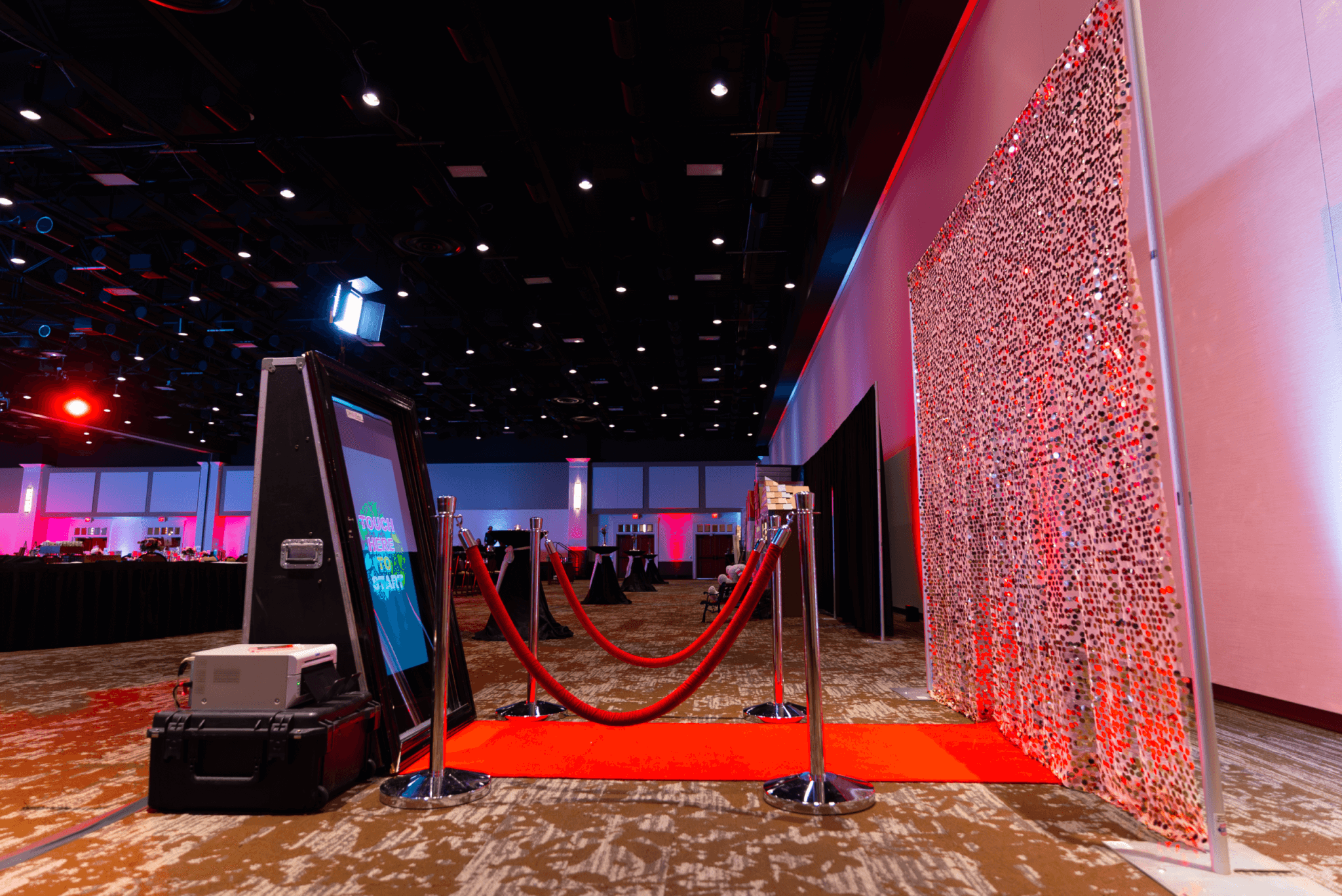 Hershey Lodge Image-18 A photo booth setup with a red carpet, stanchions, and a decorative backdrop in a large, dimly lit event space.