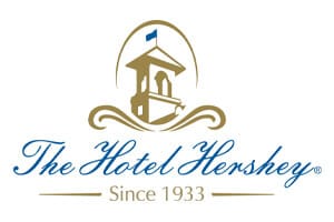 venue-logo-hotel hershey The Hotel Hershey logo with an illustration of a bell tower, a blue flag, and text reading "The Hotel Hershey Since 1933.
