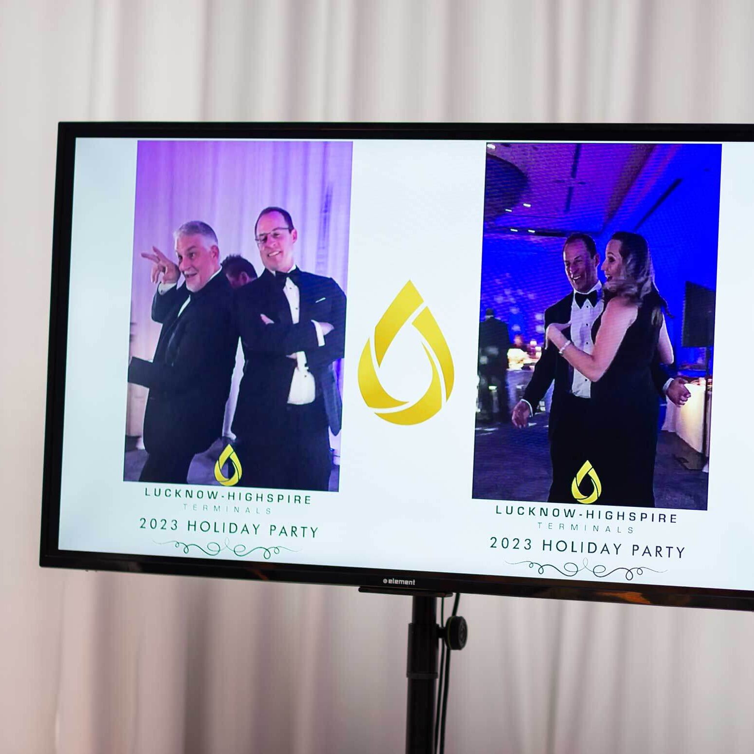 A monitor displays two photos from the Lucknow-Highspire Terminals 2023 Holiday Party, showing guests dancing and posing together in formal attire.