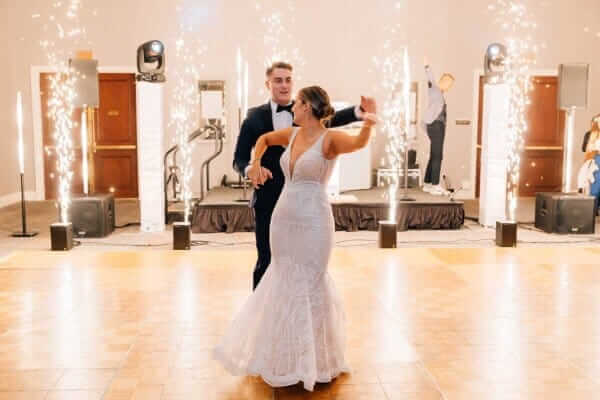First dance on a wooden floor with indoor sparklers and Klock Entertainment speakers in the background