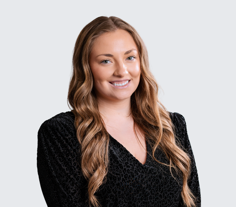 Headshot of a smiling woman with long brown hair wearing a black textured top.