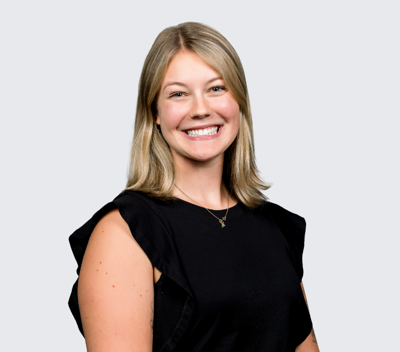 A smiling woman with shoulder-length blonde hair wearing a black top.